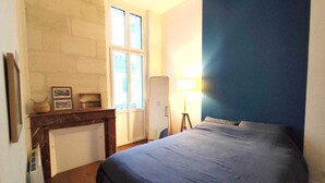 Een slaapkamer met een bed, een open haard, een lamp en een raam.