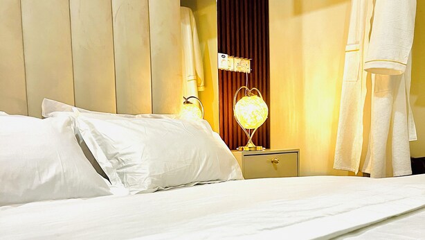 Une chambre d’hôtel avec un lit, une table de chevet, une lampe et un peignoir suspendu.