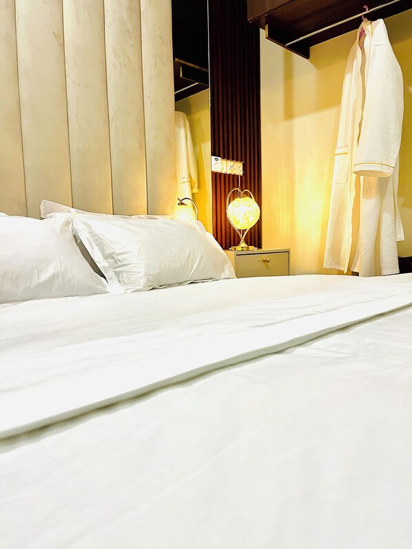 A hotel room with a bed, a nightstand, a lamp, and a hanging robe.