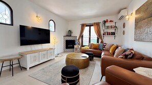 Ein Wohnzimmer mit Flachbildfernseher, Kamin, Sofa und Bücherregal.
