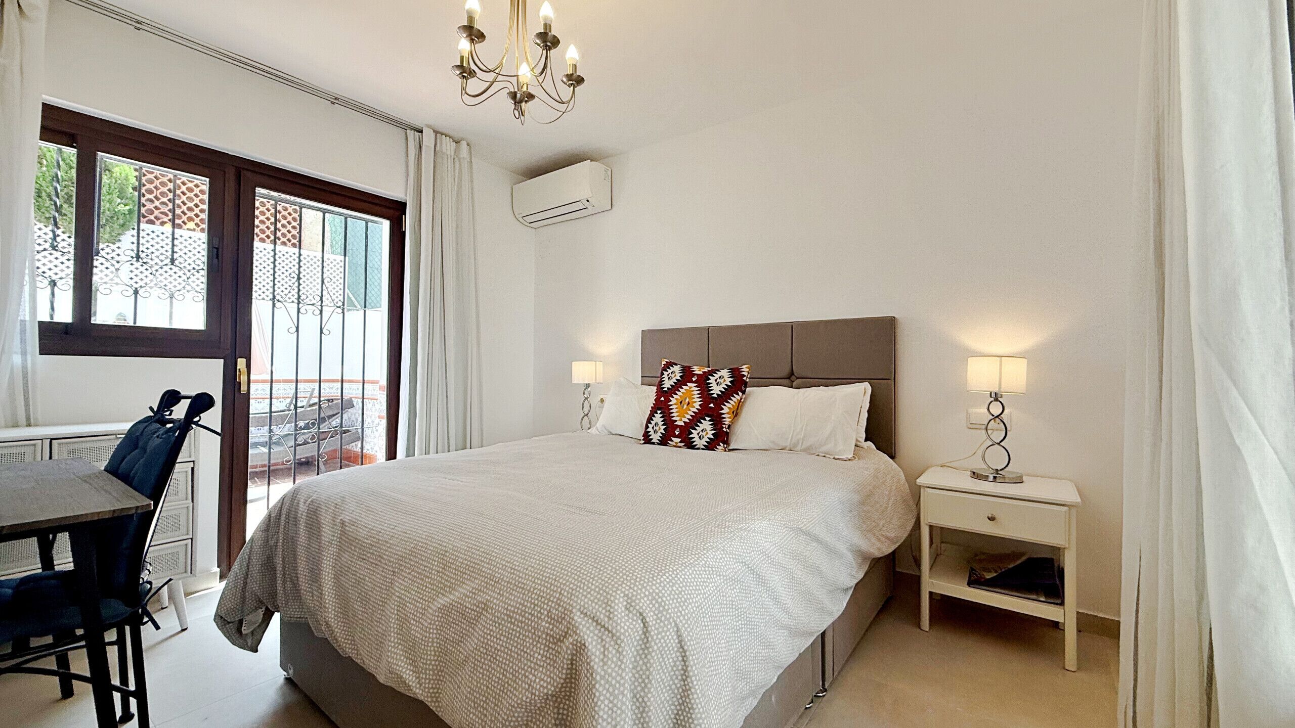 A hotel room with a bed, bedside tables, a desk, and a chair.