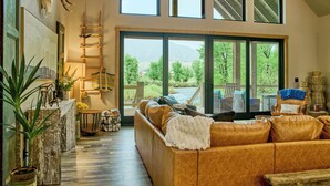 A spacious living area with a large window, a wooden ladder, and a leather sofa. - RiverBend Rio (South Fork)
