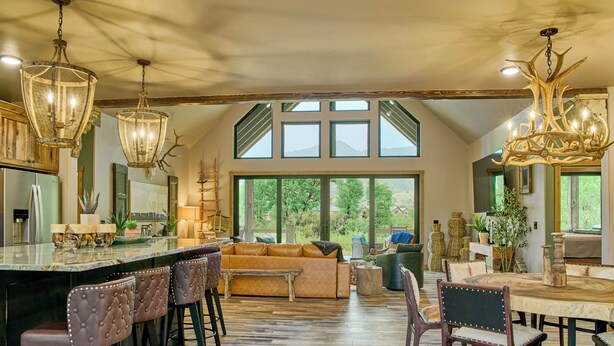 A spacious kitchen with a large island, bar stools, a sofa, and a dining table. - RiverBend Rio (South Fork)