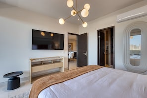Ein modernes Hotelzimmer mit einem großen Bett, einem Schreibtisch, einem Stuhl, einem Spiegel und einer Deckenleuchte.