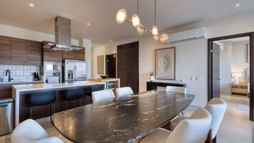 A modern kitchen with a central island, stainless steel appliances, and a dining area with a marble table.