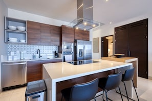 Eine moderne Küche mit Holzschränken, Edelstahlgeräten und einer zentralen Kochinsel mit Barhocker.