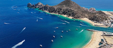 An aerial view of a coastal area with a beach, boats, and buildings.