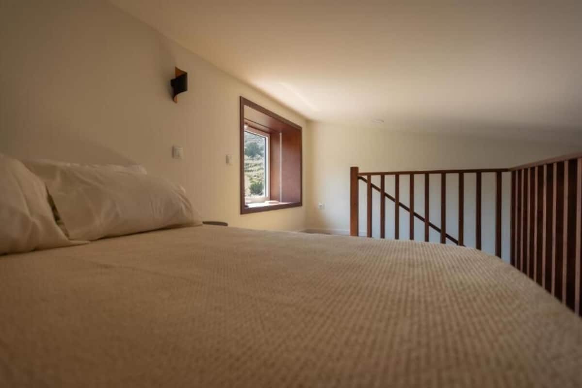 Un dormitorio con una cama grande, una ventana y una baranda de madera.