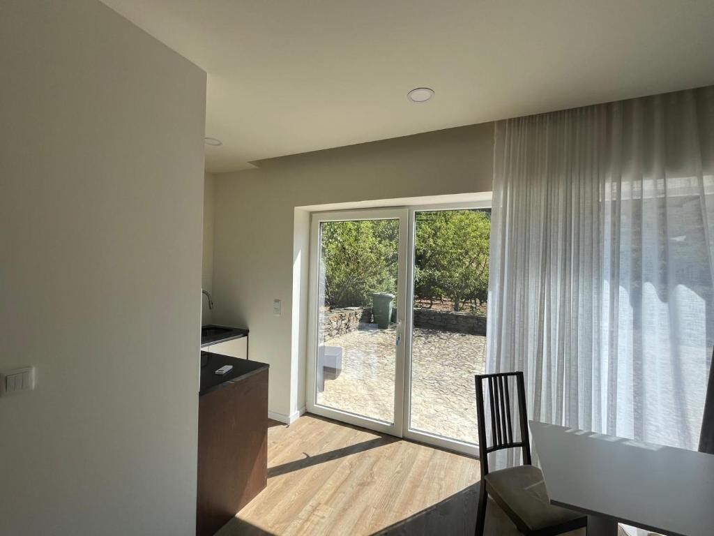 A room with a sliding glass door leading to an outdoor area, a dining table, and a kitchen counter.