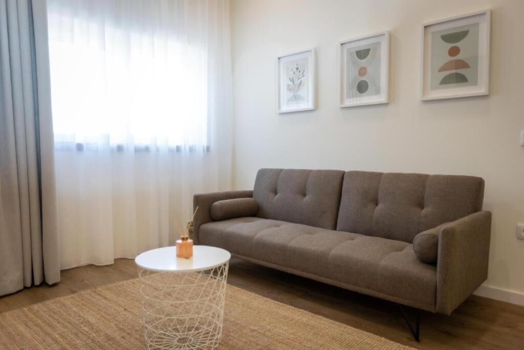 A living room with a sofa, a round coffee table, and three framed artworks on the wall.