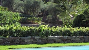 A swimming pool with a stone wall and green grass.