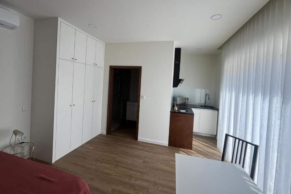Un dormitorio con cama, armario, kitchenette y baño.