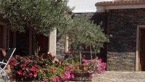 A stone building with a courtyard, potted plants, and a wooden bench.