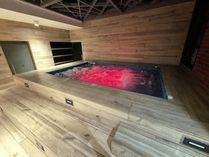 Ein Wellnessbereich mit Whirlpool, Holzboden und Backsteinwand.