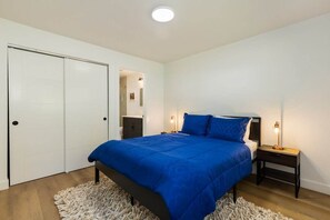 A bedroom with a bed, bedside tables, a wardrobe, and a light fixture. - Stylish Eastside 3BR Family Home | Prime Location! (Bellevue)