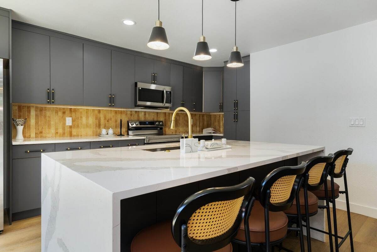 A modern kitchen with dark cabinetry, a large island, and bar stools.