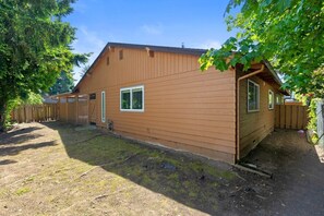 A single-story wooden house with a fenced yard, a covered porch, and a clear sky. - Stylish Eastside 3BR Family Home | Prime Location! (Bellevue)
