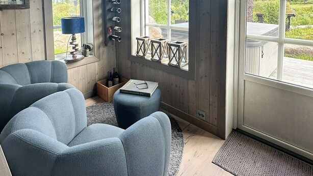 Una habitación con techo de madera, un reloj de pared grande, un sofá, una mesita y una ventana con vista a la vegetación.