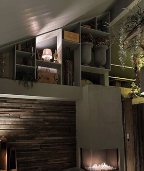 A multi-level interior with a fireplace, shelves with decorative items, and a sign indicating a champagne brand. - Modern mountain cabin near Nesfjellet golf course (Nesbyen)