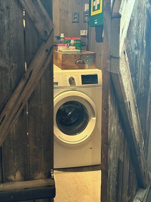 A washing machine in a laundry room with wooden walls and a staircase. - Modern mountain cabin near Nesfjellet golf course (Nesbyen)