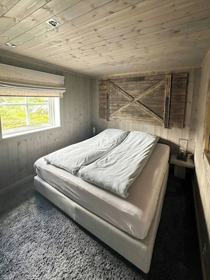 A bedroom with a bed, a window, and wooden walls. - Modern mountain cabin near Nesfjellet golf course (Nesbyen)