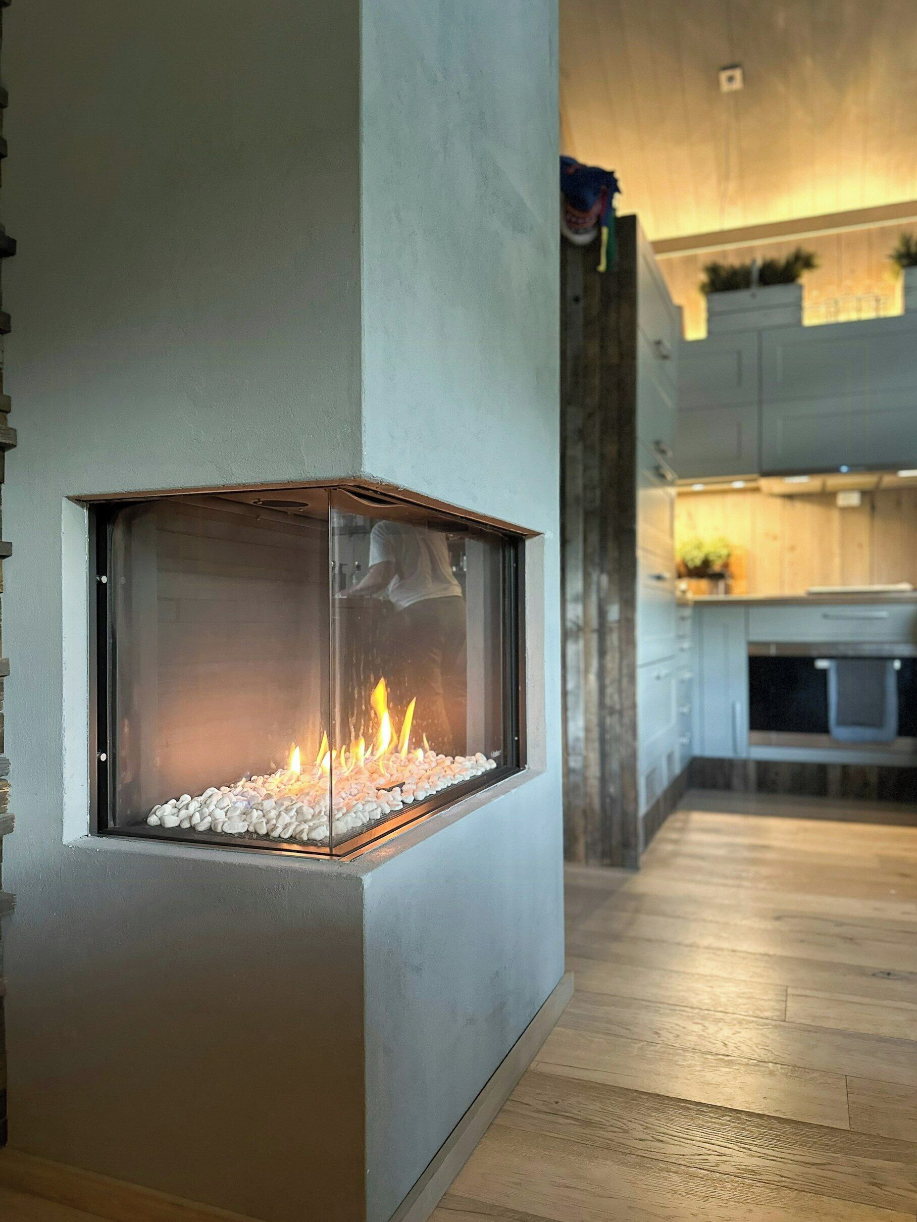 A modern kitchen with a built-in fireplace, wooden flooring, and a visible kitchen counter.