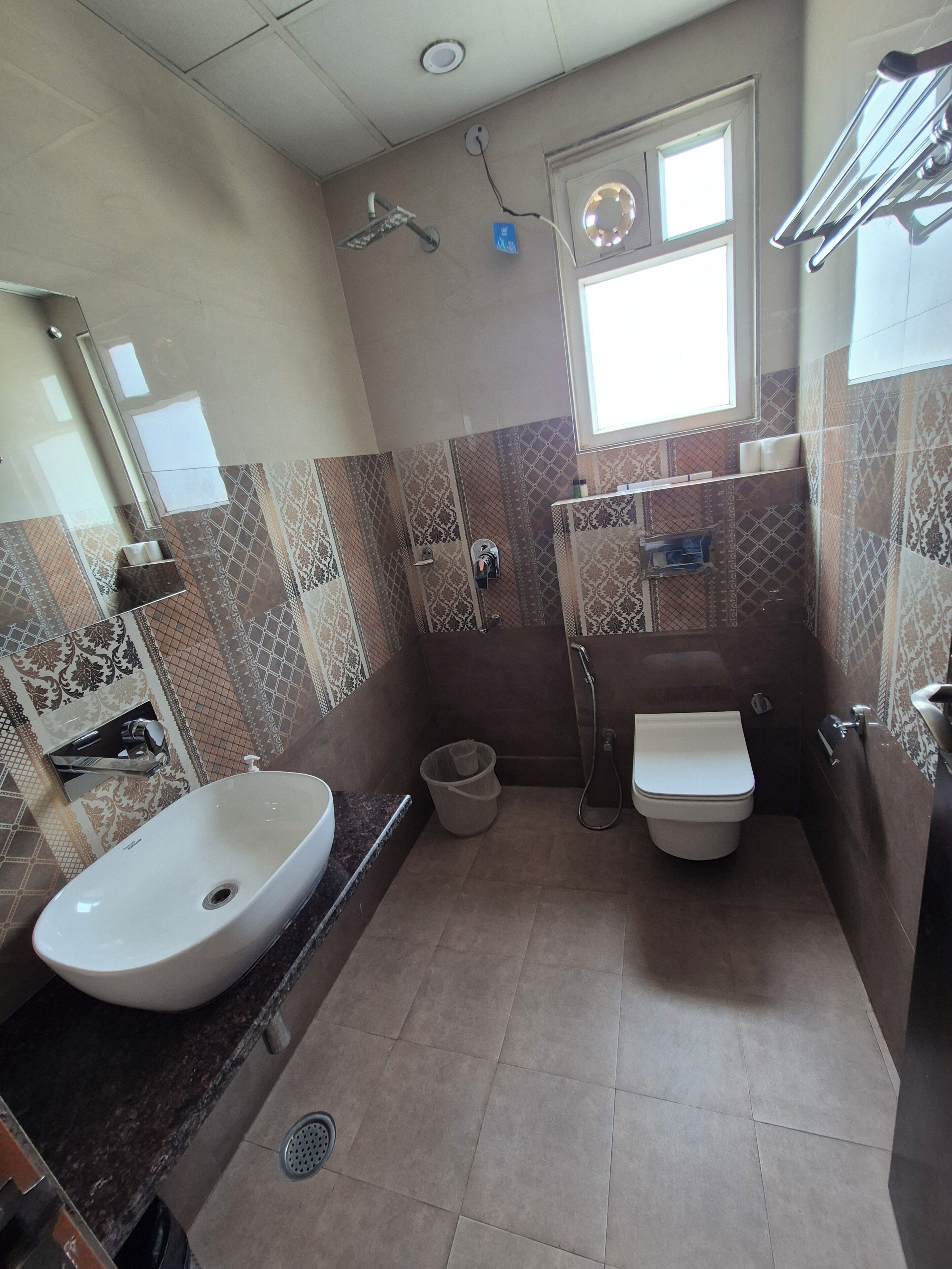 Une salle de bain avec un lavabo, des toilettes, une douche et une fenêtre.