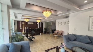 Een moderne hotel lobby met een receptiebalie, een zithoek en een kroonluchter.