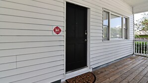 Een huis met een zwarte deur, een rood bord met daarop 'RF' en een houten veranda.