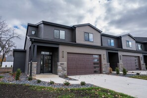 A modern two-story house with a garage, stone accents, and a landscaped front yard.