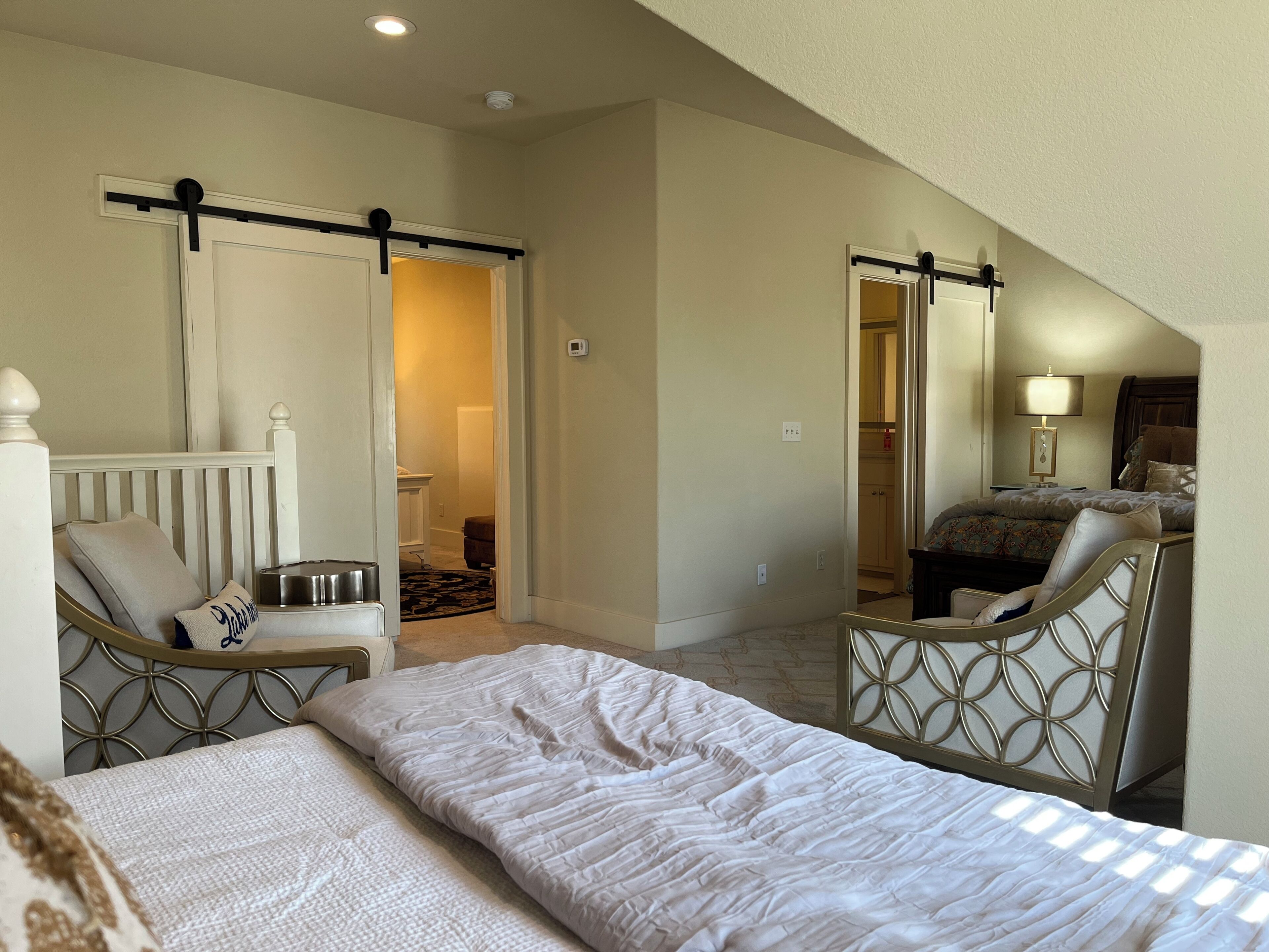 Une chambre à coucher avec un lit, une chaise, un bureau et un miroir.