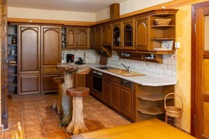 A kitchen with wooden cabinets, a sink, and a dining table. - Apartment Josephine (Torgau)