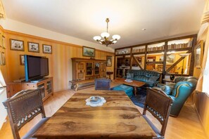 Un salon avec une table à manger en bois, un canapé bleu et un téléviseur posé sur un meuble en bois.