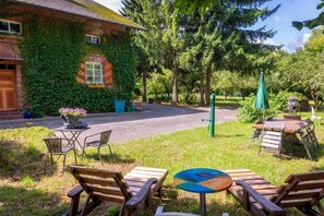 Un bâtiment en briques recouvert de lierre, avec des tables à l’extérieur et un chemin pavé.