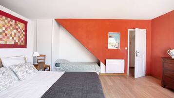 Un dormitorio con una cama, una silla, un escritorio, un aparador y una puerta que da a otra habitación.