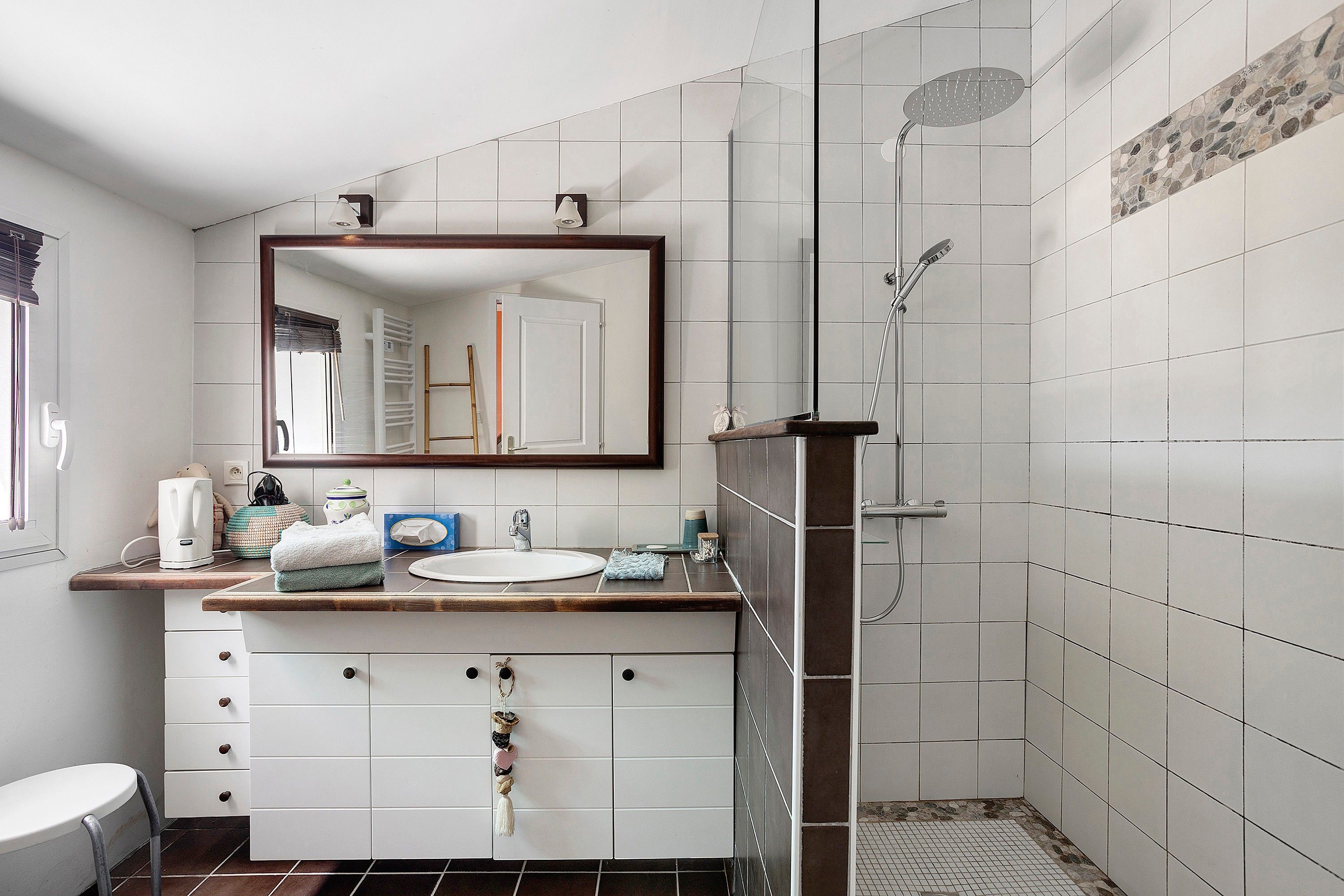 A bathroom with a white sink, a mirror, a shower, and a toilet.