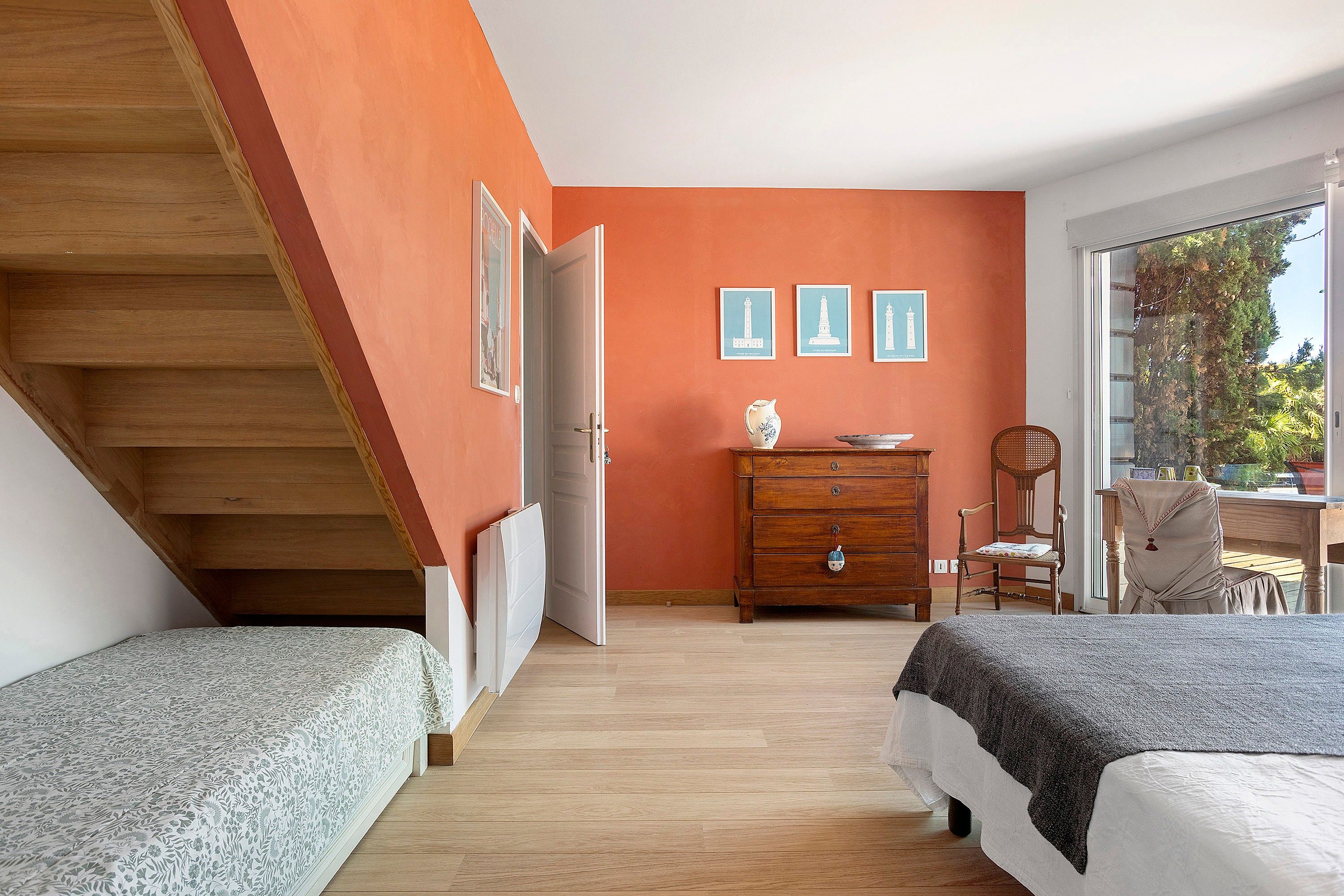 Ein Schlafzimmer mit zwei Betten, einem Schminktisch, einem Stuhl und Blick ins Freie.