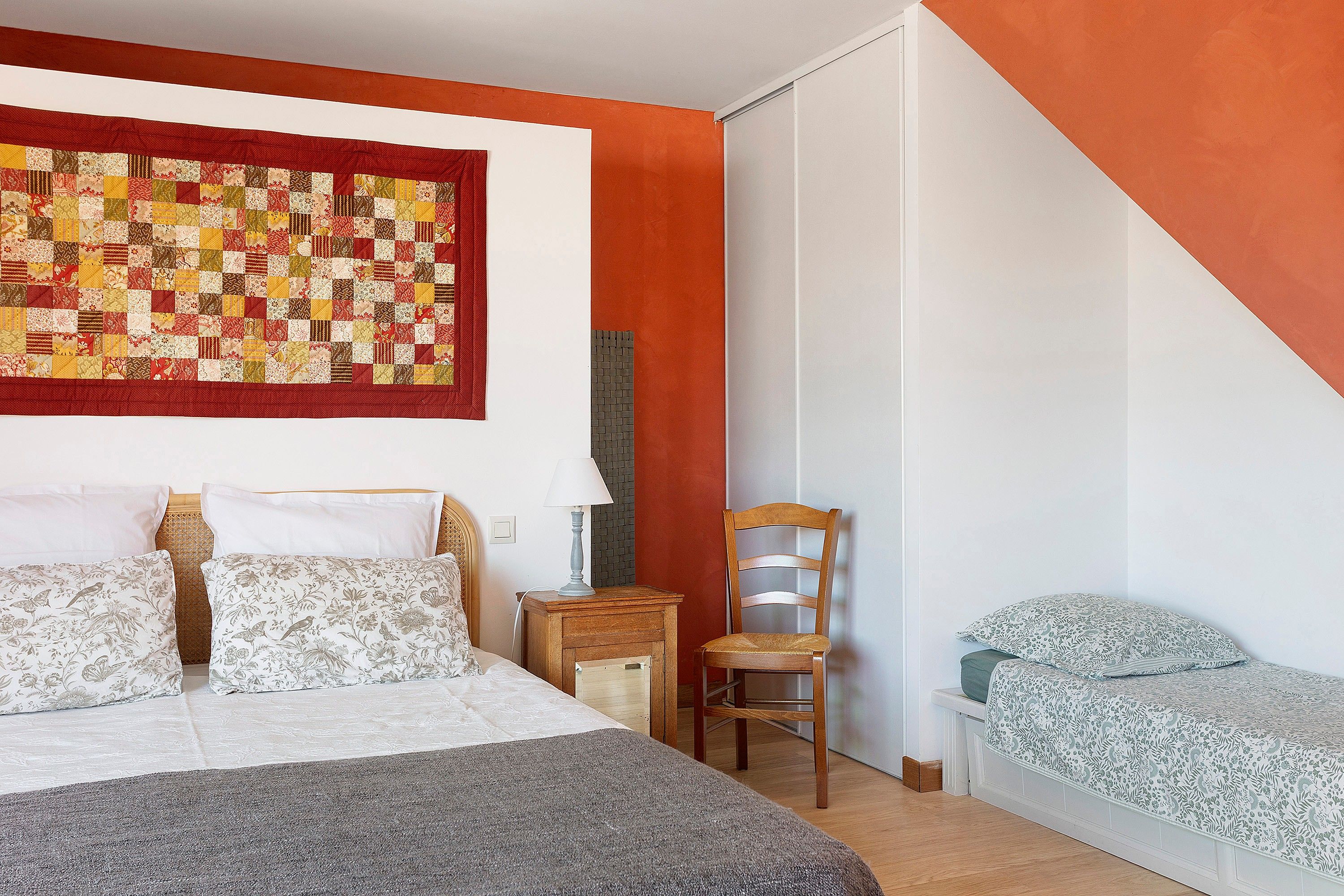 A bedroom with a bed, a chair, a nightstand, and a small table.