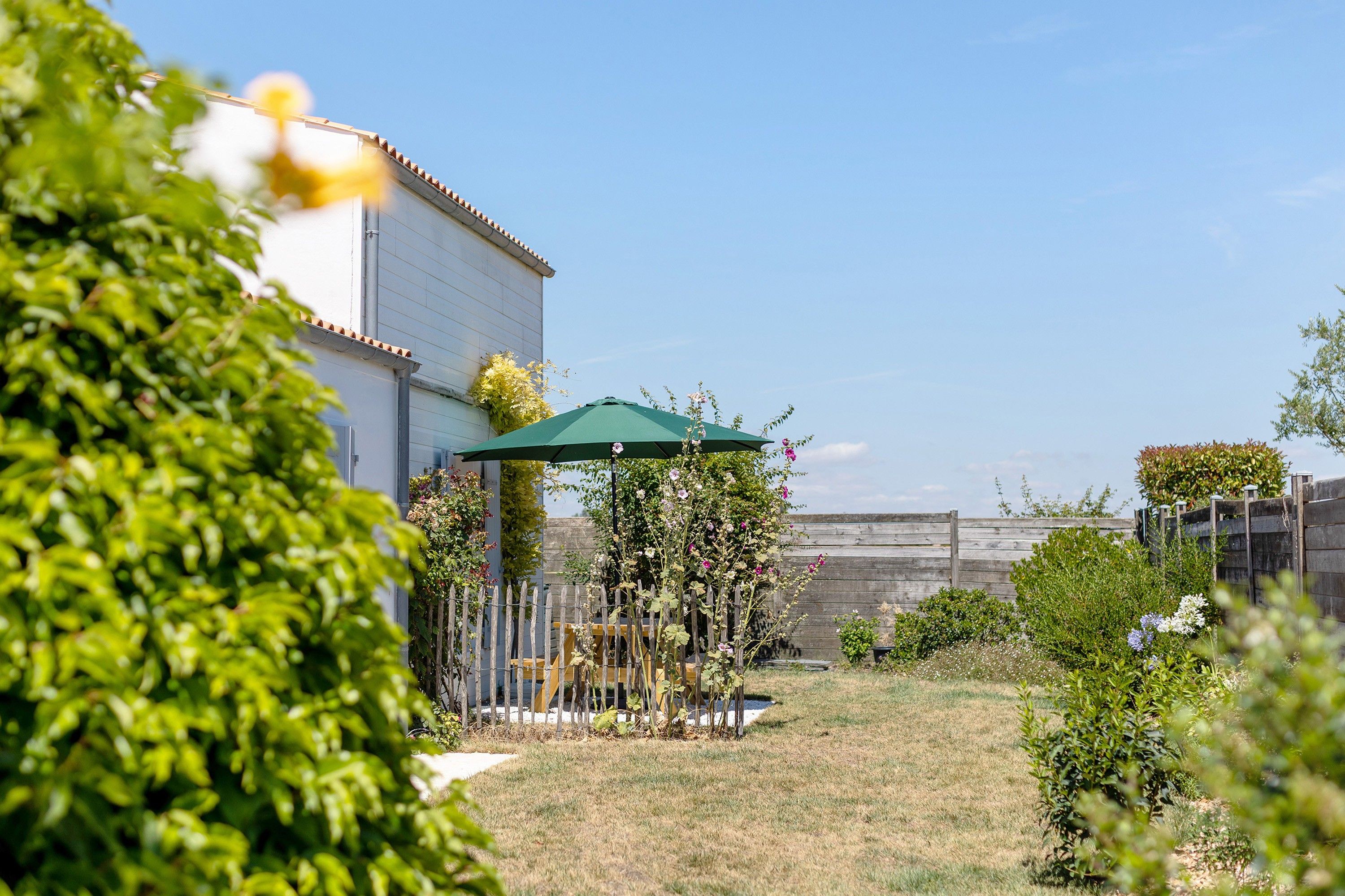 Un cortile residenziale con patio, recinzione in legno e diverse piante.