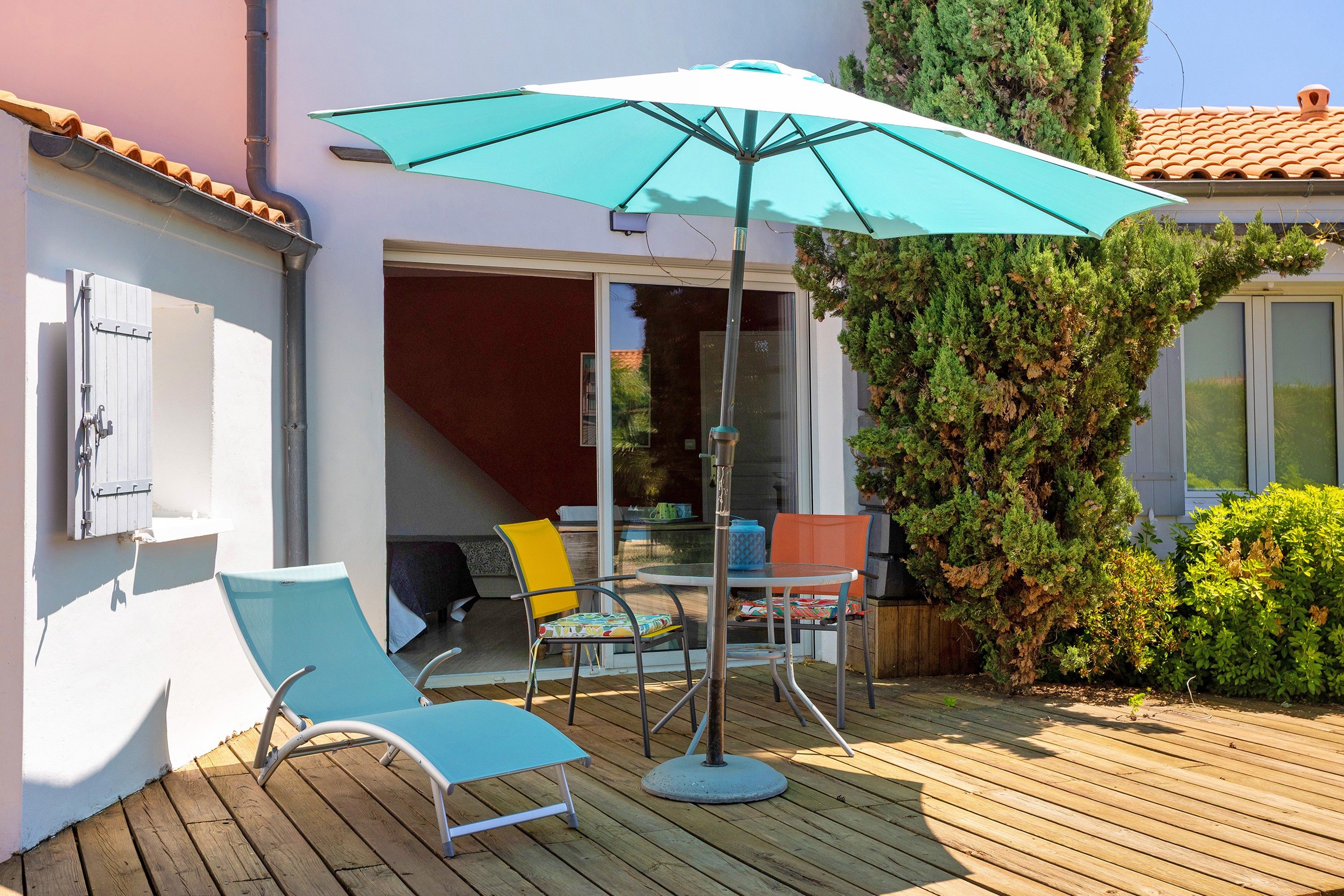 Une terrasse extérieure avec une table, des chaises et un grand parasol.