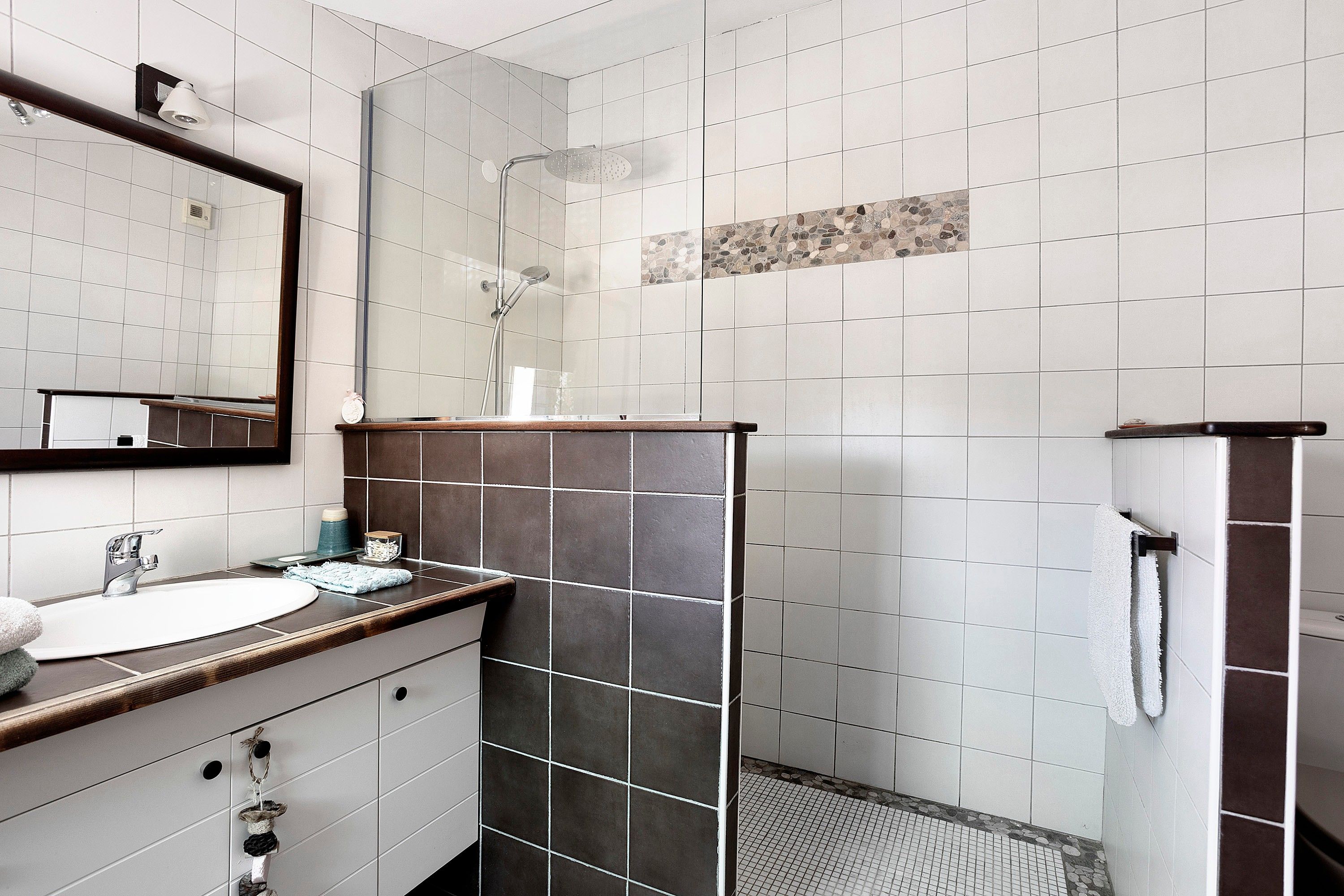 A bathroom with a sink, mirror, and shower area.