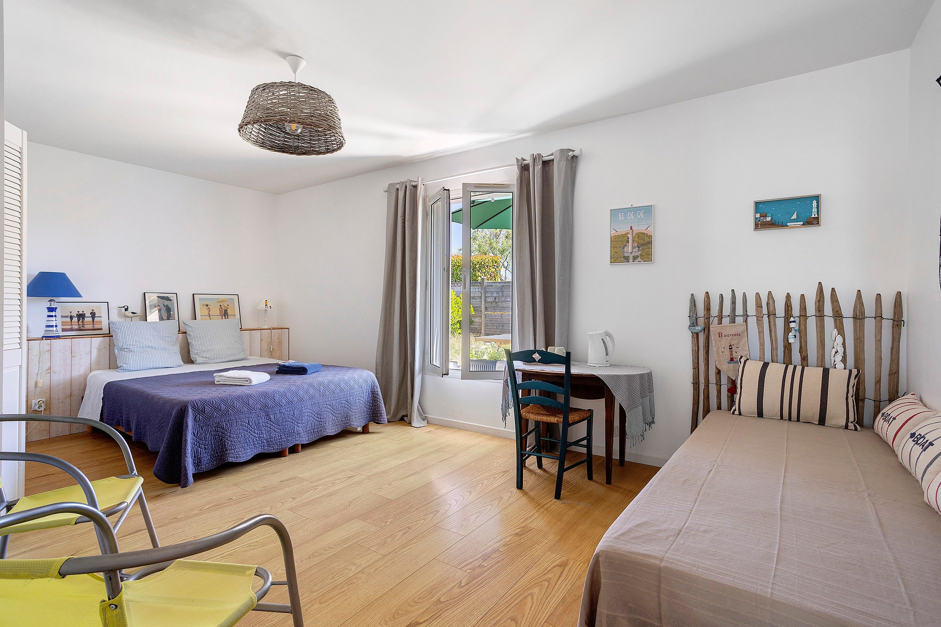 A room with a bed, a desk, a chair, a table, and a window with curtains.