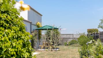 Un cortile residenziale con patio, recinzione in legno e diverse piante.