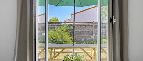 A sliding glass door with a green umbrella, wooden deck, and potted plants.