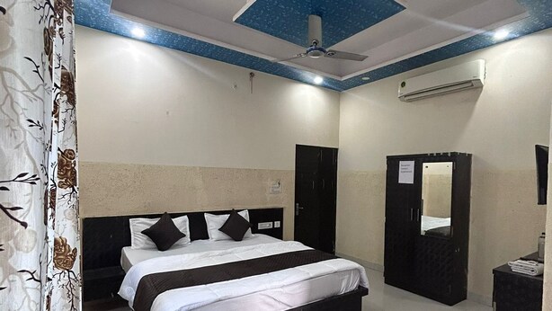 Hotelkamer met een bed, een rode bank, een glazen salontafel, een airconditioner en een plafondventilator.