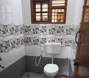 A bathroom with a toilet, a shower, and a window with bars.