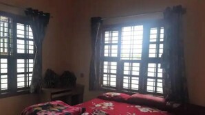 Een slaapkamer met een bed, nachtkastje en een raam met gordijnen.