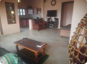 A living room with a sofa, a wooden coffee table, a television, and a kitchen in the background.