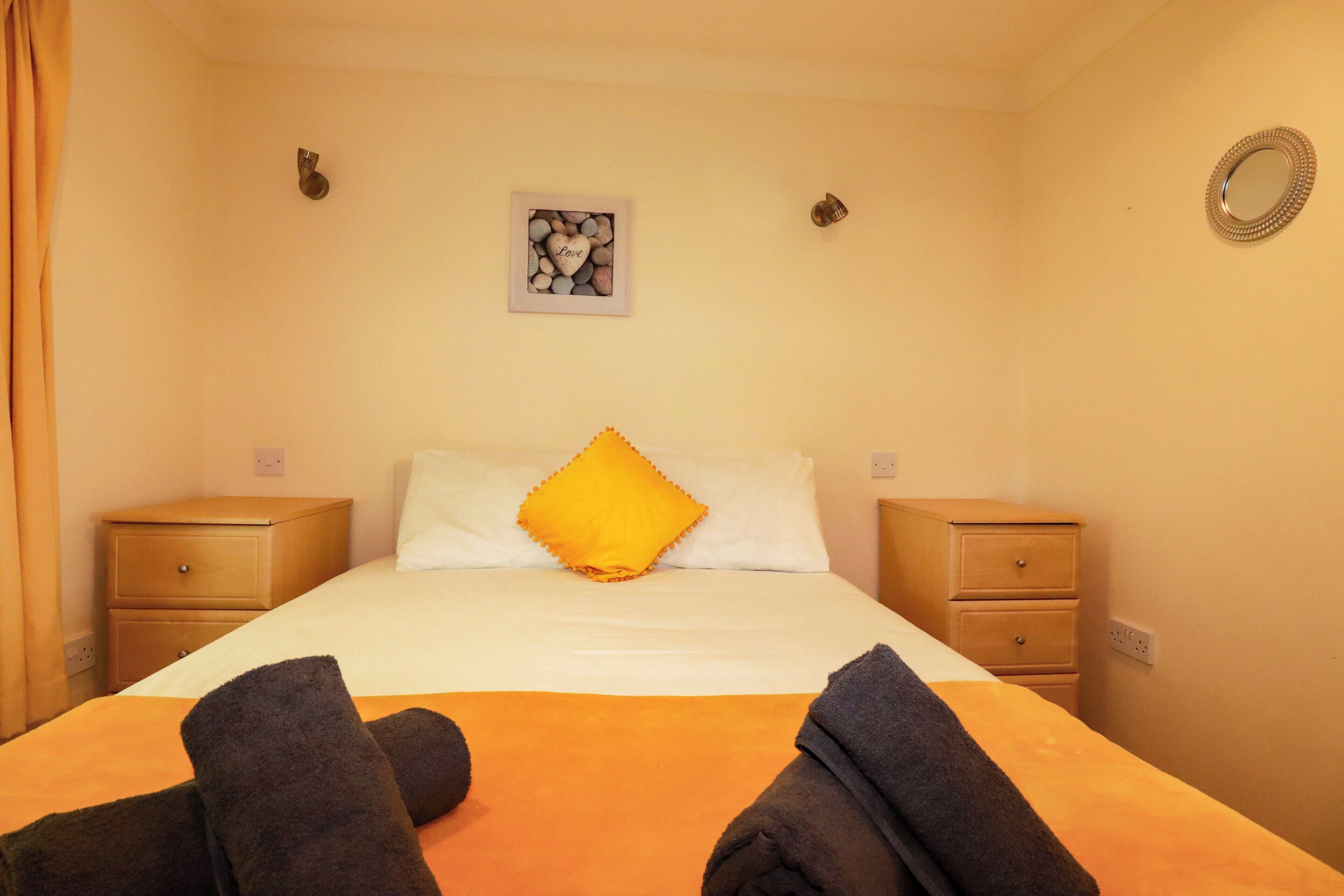 A hotel room with a bed, two nightstands, a wall-mounted picture, and a mirror.