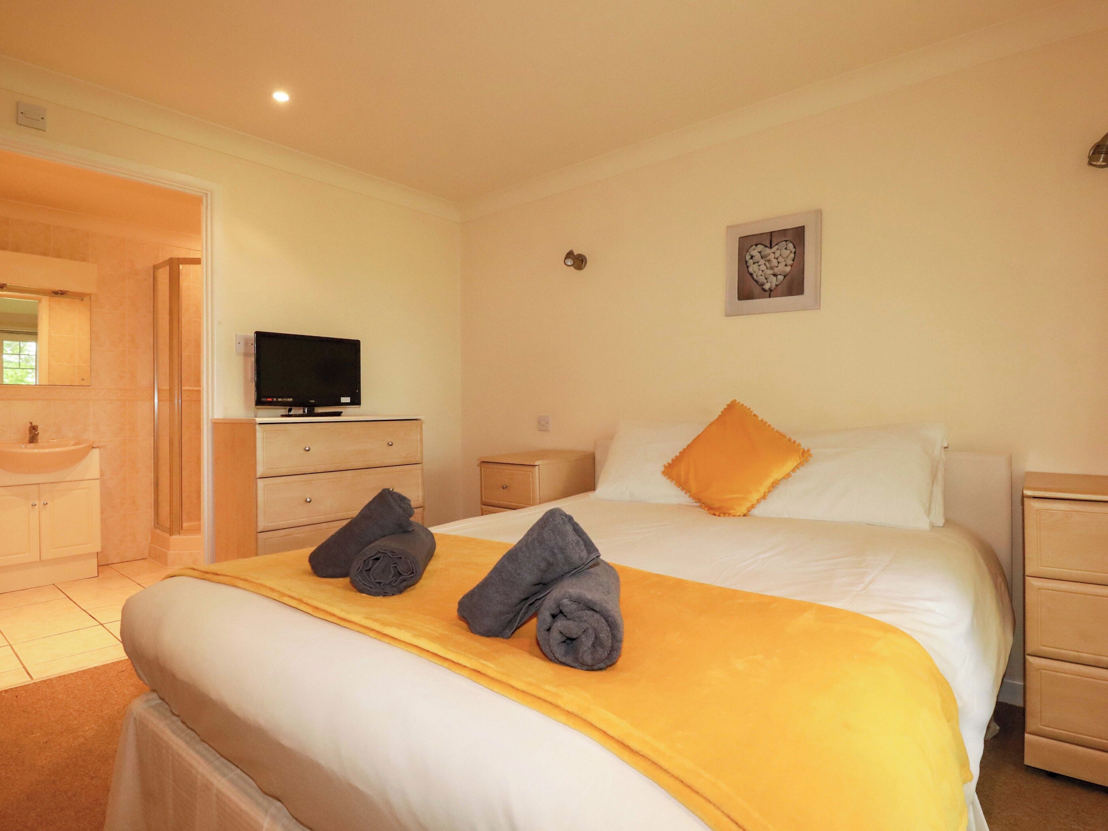 A hotel room with a bed, a television, a bathroom, and a small bedside table.
